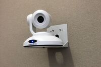 Camera mounted to a wall and instructor enabled adjustments to the lens to allow the instructor to be "seen" by the camera in more locations around the room