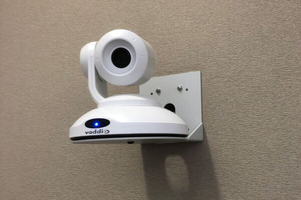 Camera mounted to a wall and instructor enabled adjustments to the lens to allow the instructor to be "seen" by the camera in more locations around the room