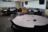 View of room with lectern center in front of markerboard and display monitors to left and right