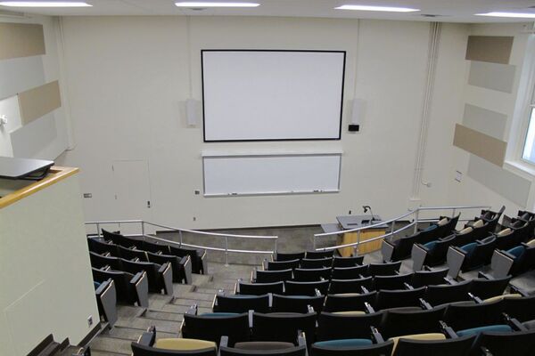 Front of room view with lectern on right in front of markerboard and projection screen above