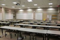 Back of room view of student table and chair seating and markerboards
