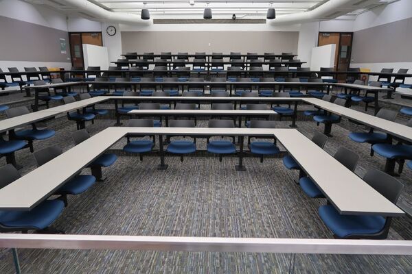 Back of room view of student fixed table and chair seating and exit doors at rear of room