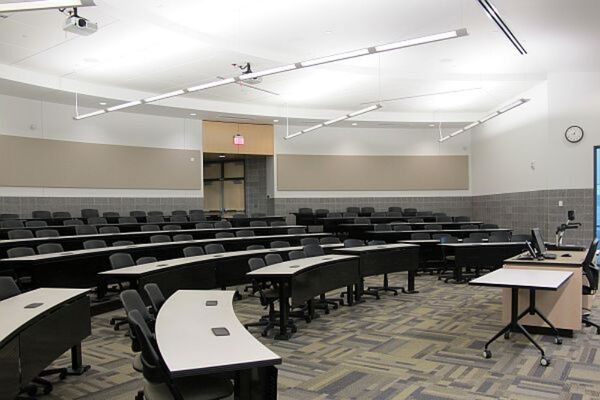 Back of room view of student tiered fixed-table and chair seating and exit door at rear of room
