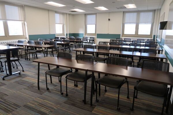 Back of room view of student table and chair seating and markerboards on right side wall