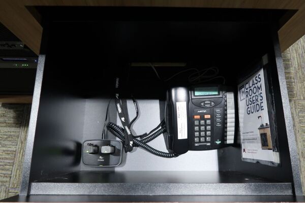 Pedestal - inside view of drawer showing two wireless mics in charging base and telephone
