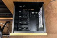 Pedestal - inside view of drawer showing two wireless mics in charging base and assistive listening devices in charger 