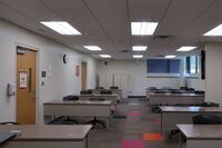 Back of room view of student table and chair seating and two exit doors on the left
