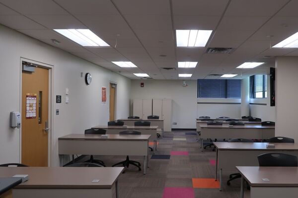 Back of room view of student table and chair seating and two exit doors on the left