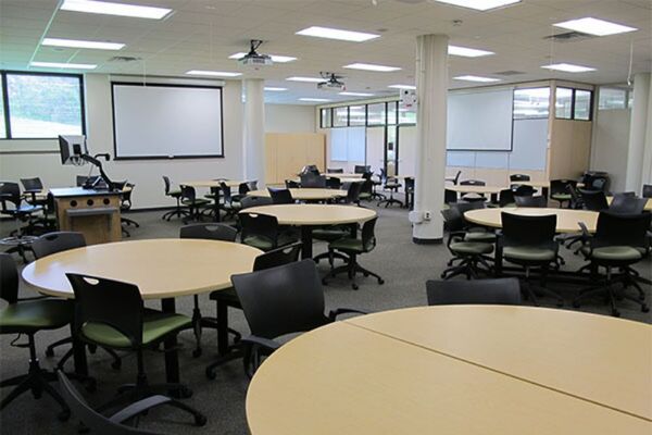 View of room showing student group table seating and exit door at right rear of room