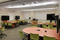 View with lectern center in front of markerboard and student table display screens to left and right 