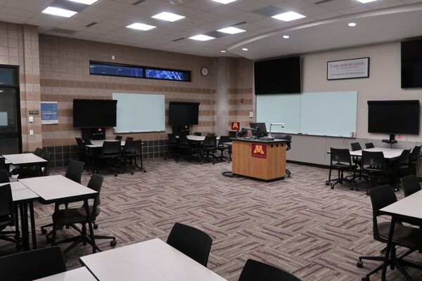 View with lectern center in front of markerboards and display screens behind and above