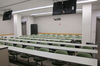 Back of room view of student fixed table and chair seating and exit doors at rear of room