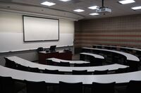 Front of room view with lectern center in front of markerboard and projection screen lowered