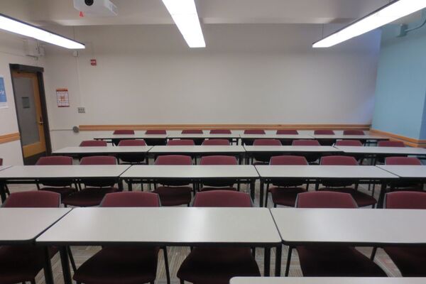 Rear of room view of student table and chair seating with rear exit at left of room