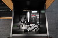 Pedestal - inside view of drawer showing two wireless mics in charging base and telephone