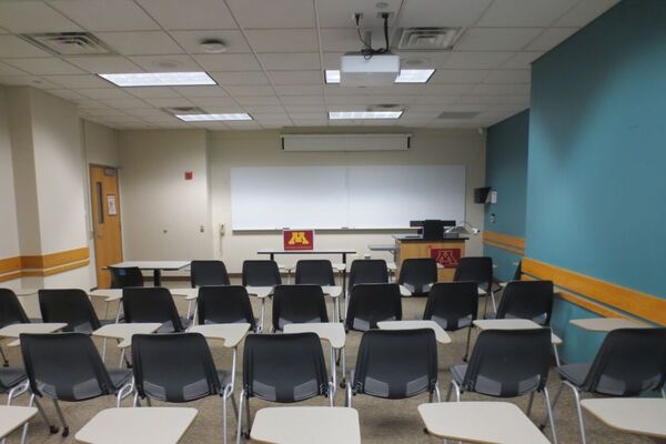 Front of room view with lectern on right in front of markerboard and projection screen partially raised